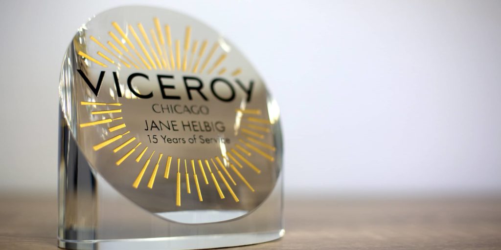 Crystal desk piece with years of service, logo, and graphics sand etched on frontside and colorfilled gold and black.